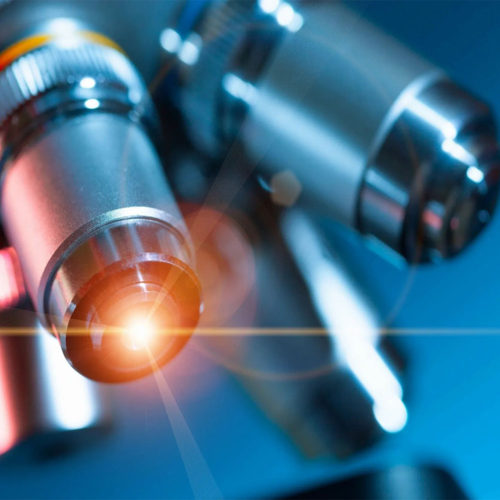 A close up of some microscopes with one glowing